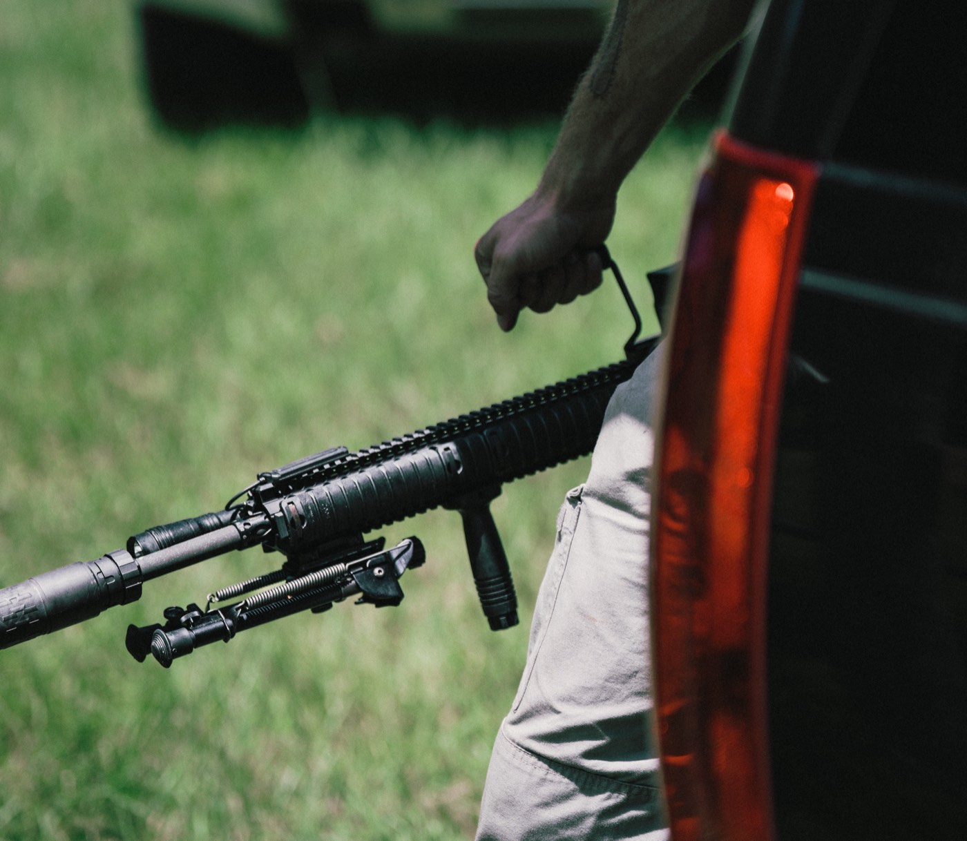 Rifle with a bipod carried alongside a vehicle