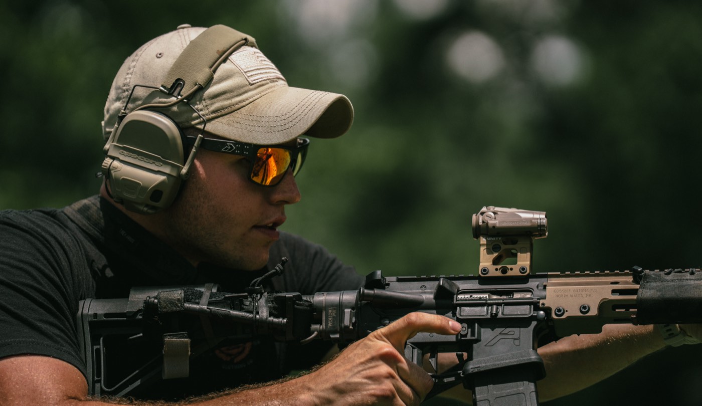 Shooter behind an FDE AR-15 with a red dot