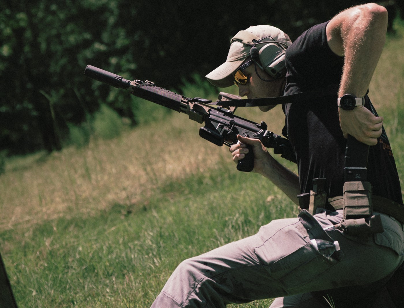 Shooter kneeling behind a suppressed AR-15 on the range