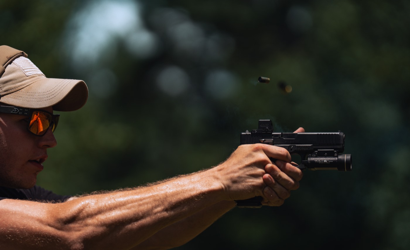 Optic-equipped pistol at full extension, brass ejecting