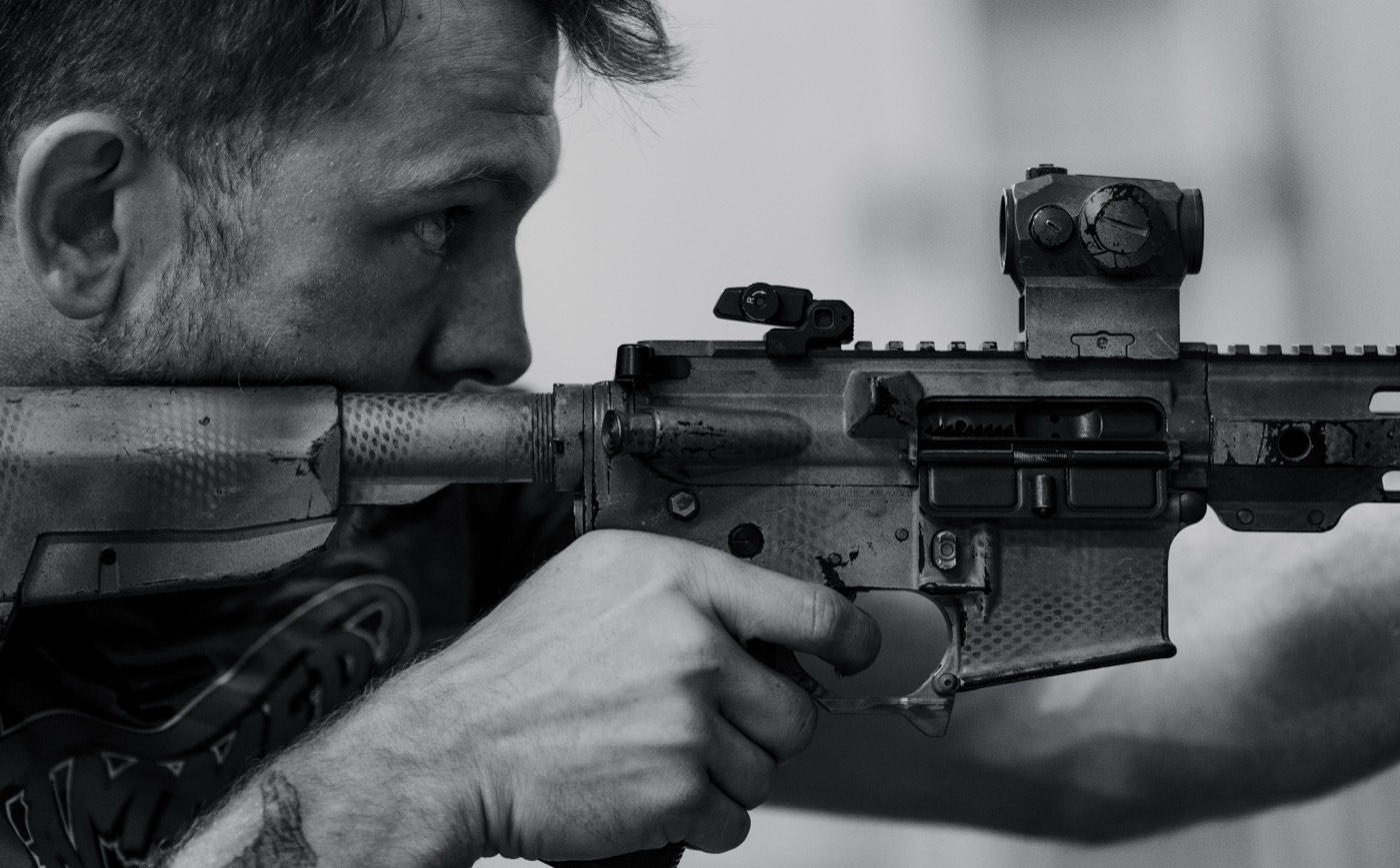 Black and white close-up of a shooter behind an AR-15