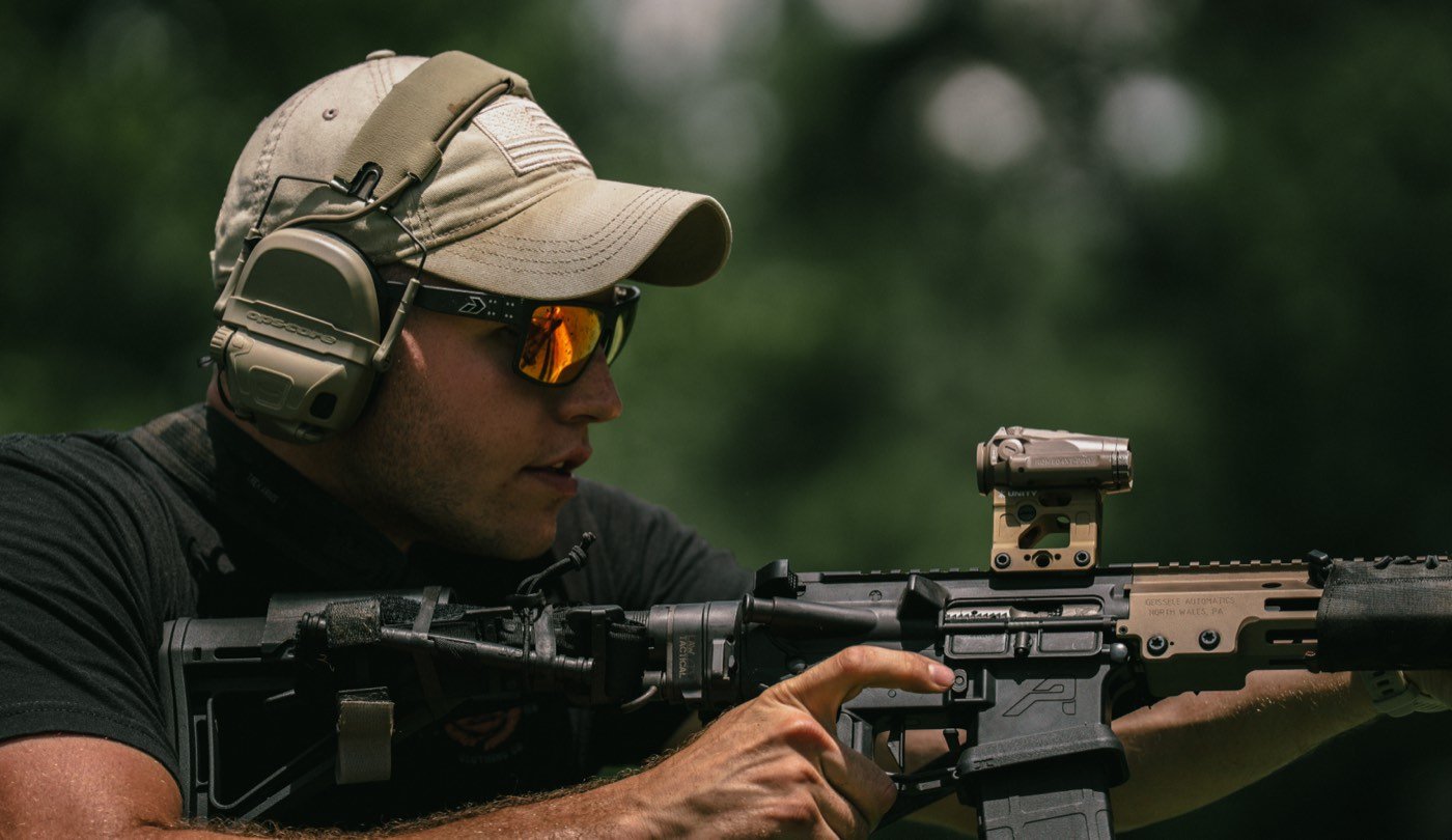 Shooter behind an FDE AR-15 with a red dot