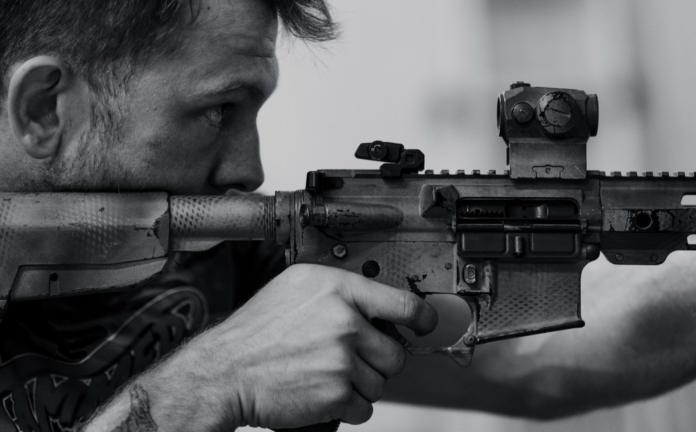 Black and white close-up of a shooter behind an AR-15